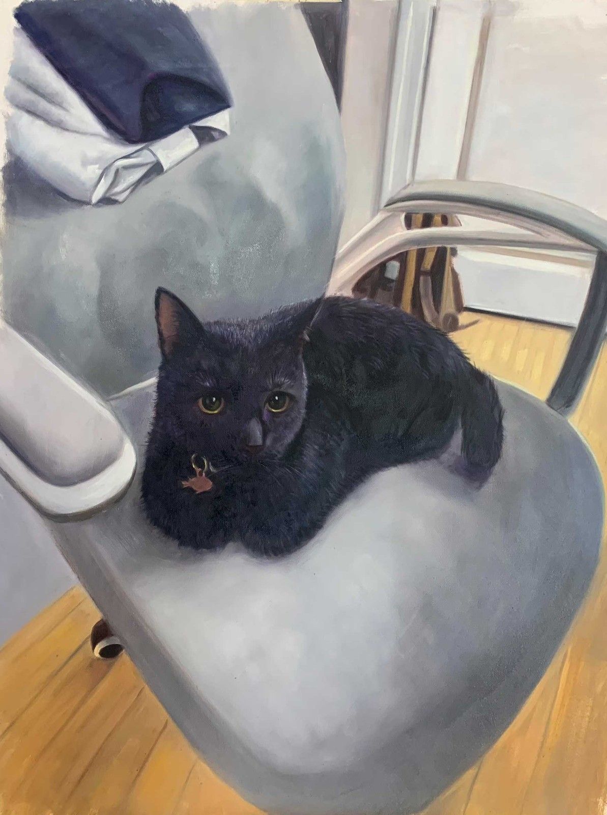 A black cat resting on a pale upholstered chair beside a draped blanket.