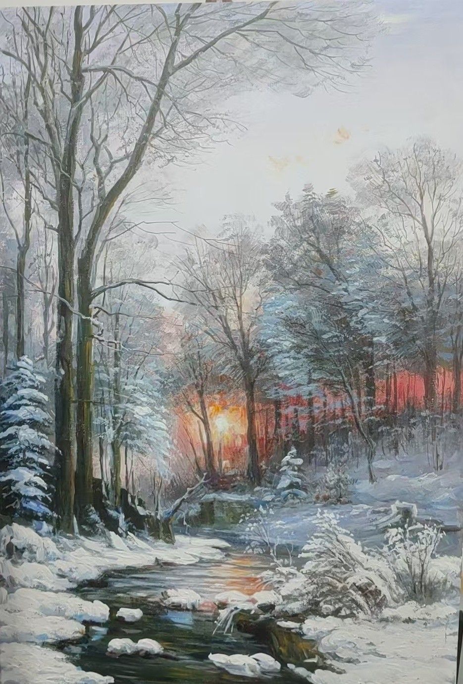 Snow-covered trees frame a stream and warm sunset glow in a quiet winter woodland.