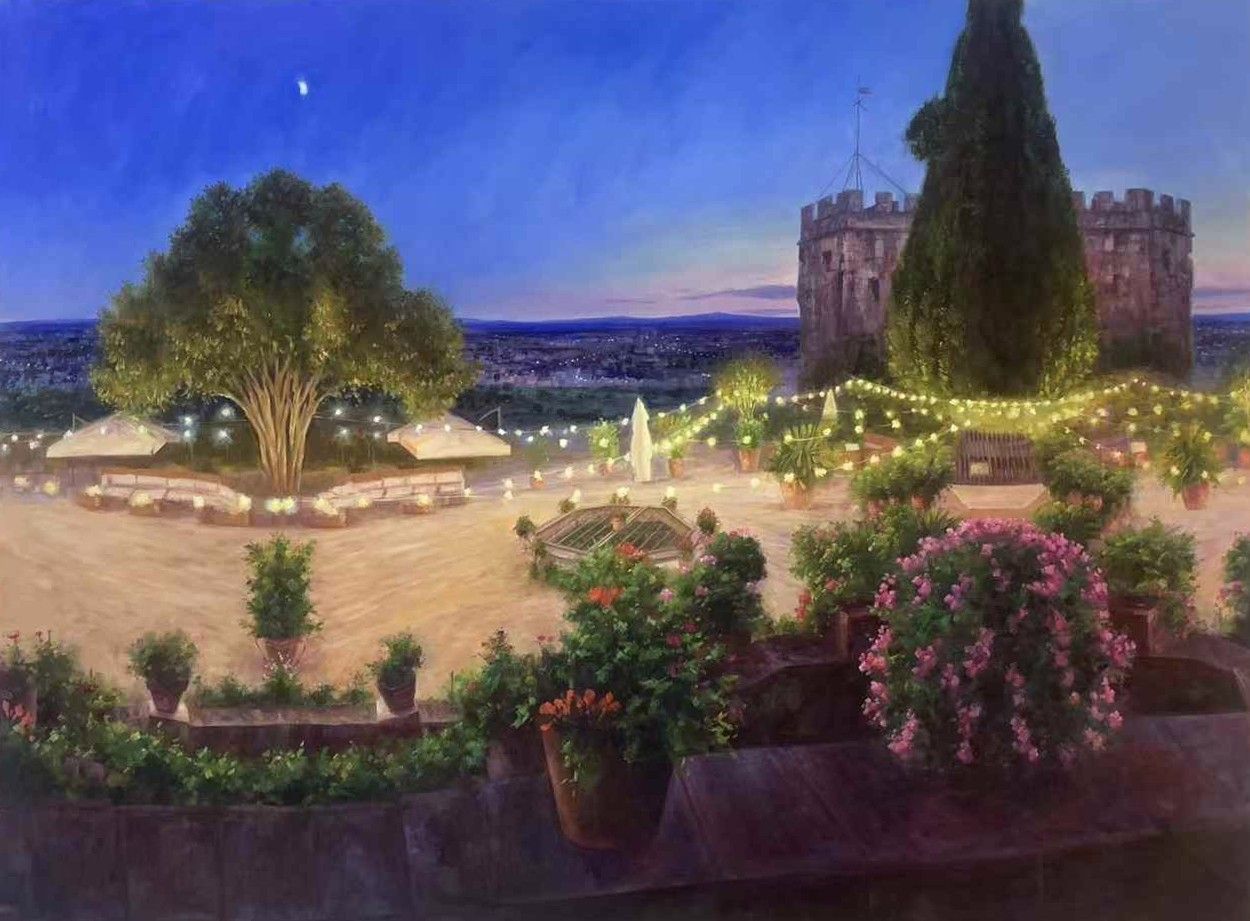 A garden terrace with string lights, flowers and distant buildings at dusk.