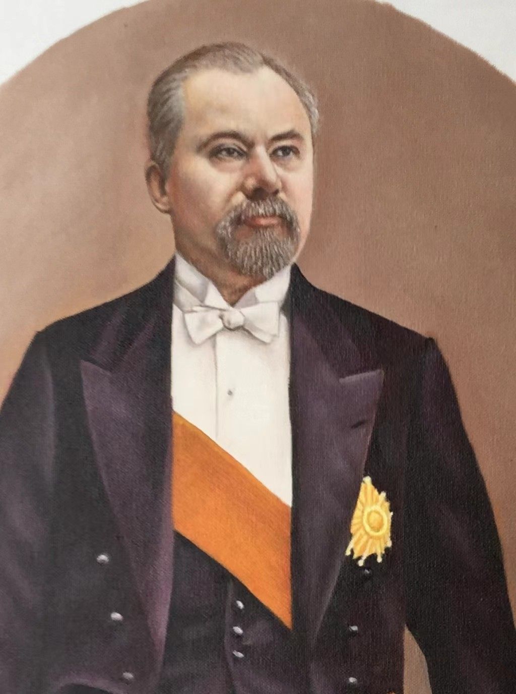 A bearded man in formal evening clothes with a sash and medals.