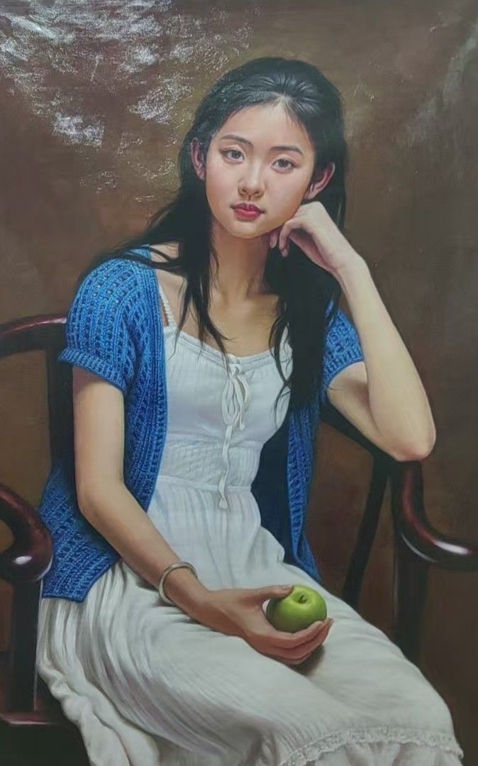 A seated young woman holds a green apple in a portrait with a warm brown backdrop.