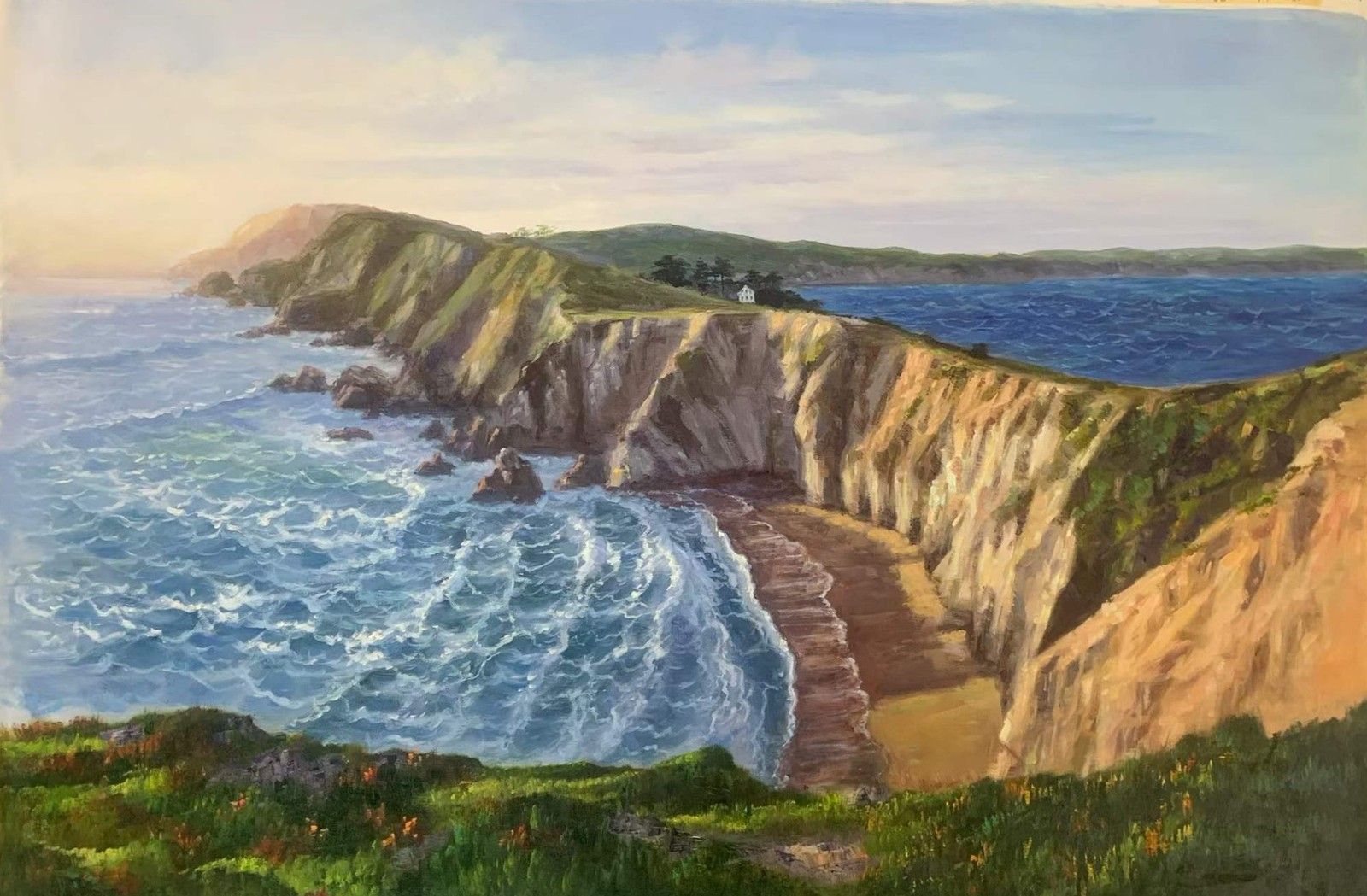 Coastal cliffs curving around a bay with blue water and breaking waves.