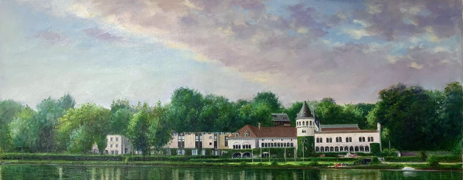 A long lakeside estate reflected in calm water beneath wooded hills.