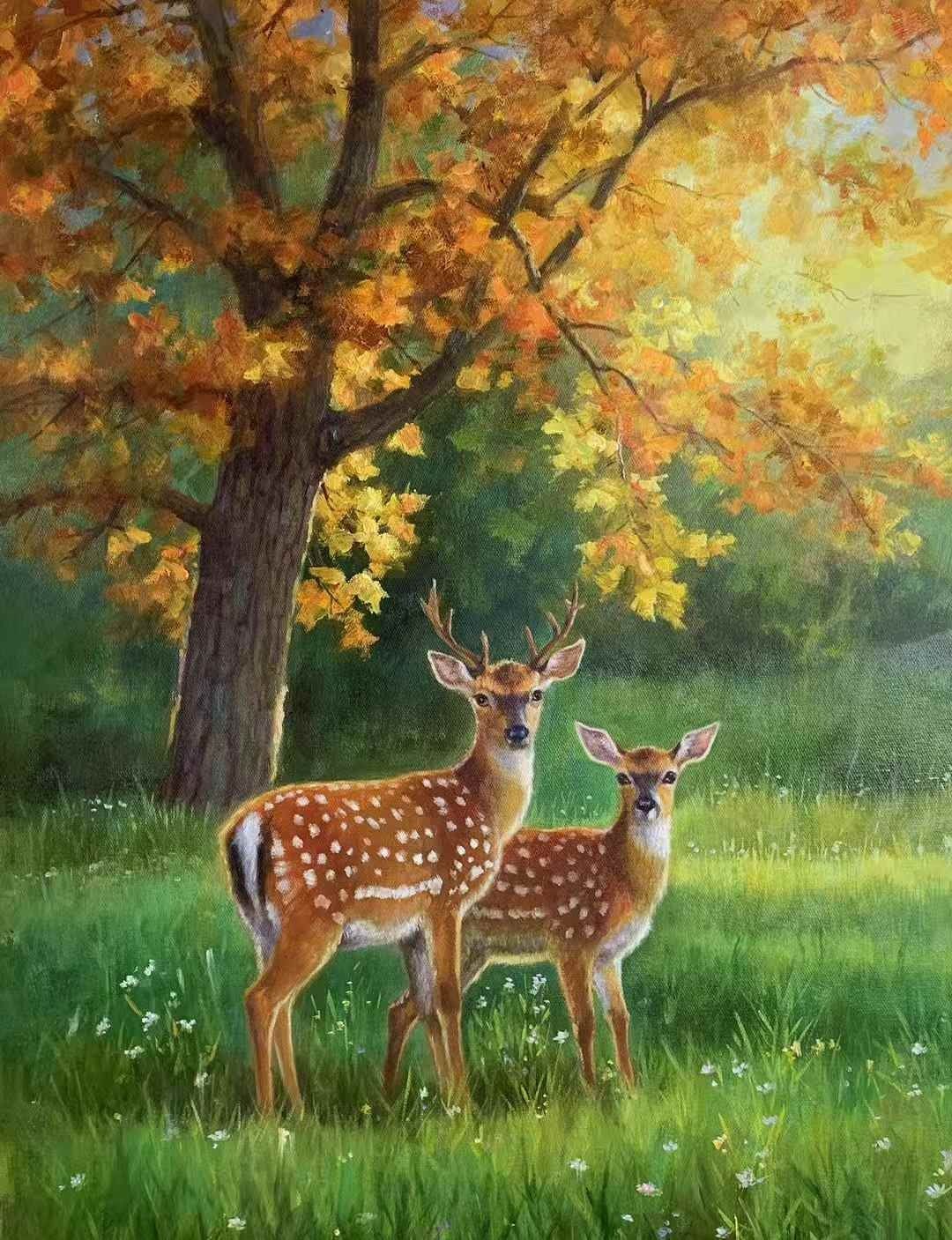 Two spotted deer in green grass beneath golden autumn trees.